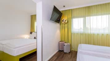 A hotel room with two beds, a flat-screen TV, and a suitcase.