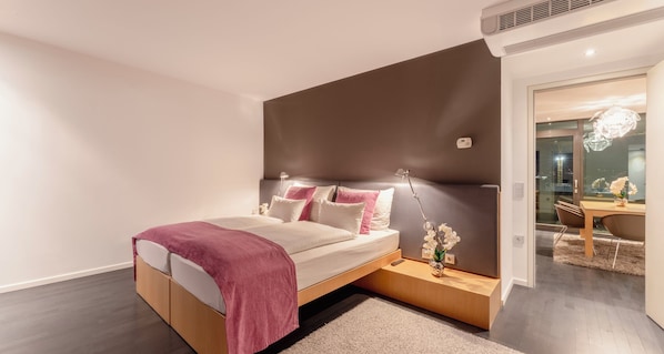 Un dormitorio moderno con cama, mesita de noche y vistas de la ciudad de noche.
