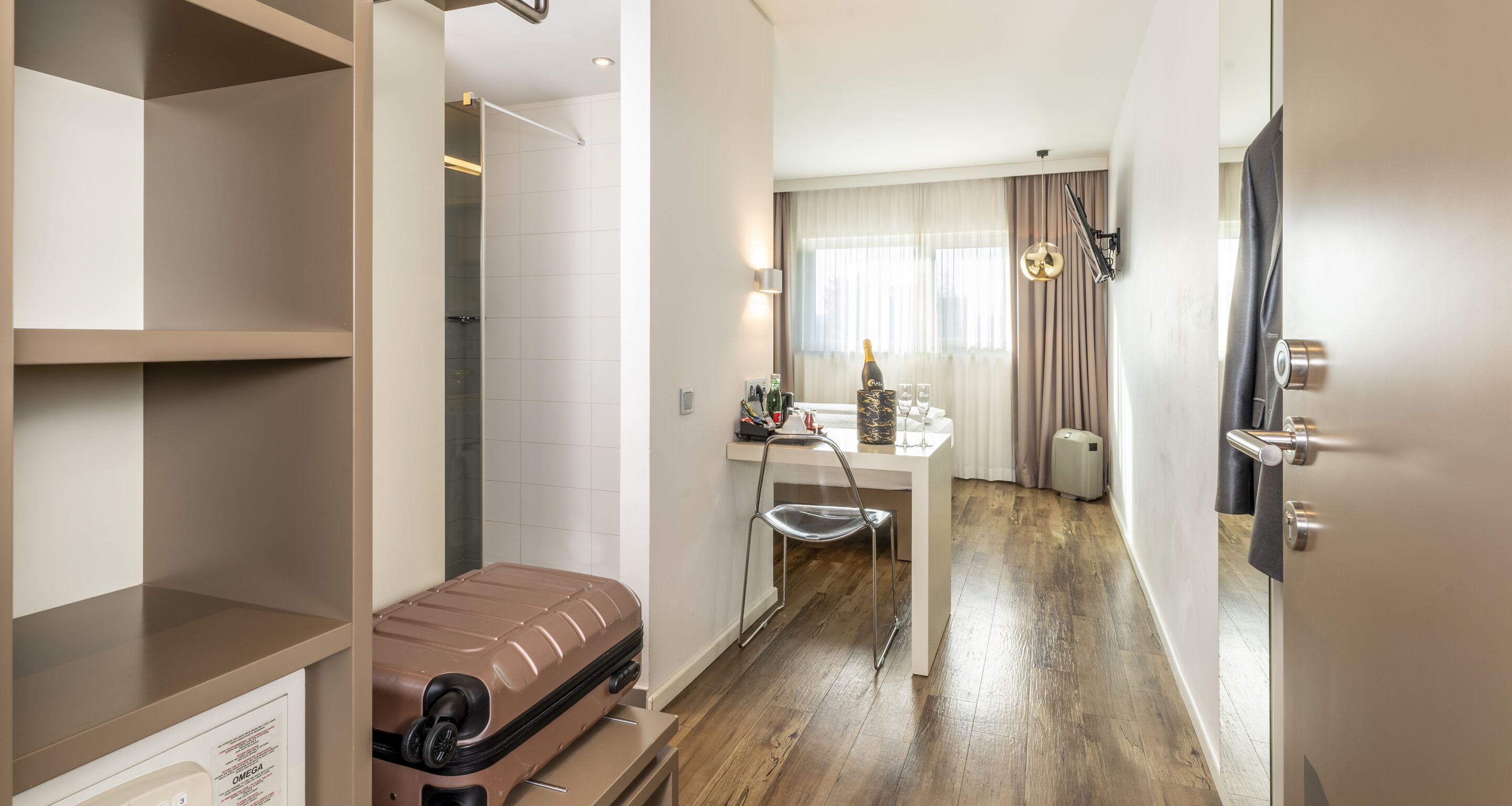 A hotel room with a wooden floor, a white desk, a chair, a minibar, a minibar fridge, a minibar sink, a minibar mirror, a minibar towel rack, a minibar soap dispenser, a minibar hand dryer, a minibar trash can, a minibar light, a minibar clock, a minibar air freshener, a minibar ashtray, a minibar bottle of water, a minibar bottle of shampoo, a minibar bottle of lotion, a minibar bottle of mouthwash, a minibar bottle of toothpaste, a minibar bottle of mouthwash, a minibar bottle of toothpaste, a minibar bottle of mouthwash, a minibar bottle of toothpaste, a minibar bottle of mouthwash, a minibar bottle of toothpaste, a minibar bottle of mouthwash, a minibar bottle of toothpaste, a minibar bottle of mouthwash, a minibar bottle of toothpaste, a minibar bottle of mouthwash, a minibar bottle of toothpaste, a minibar bottle of mouthwash, a minibar bottle of toothpaste, a minibar bottle of mouthwash