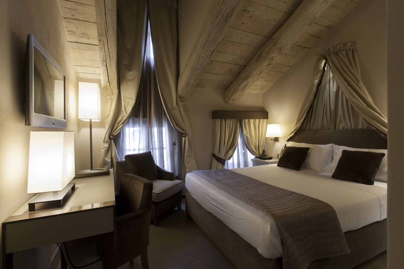 Une chambre d’hôtel avec un lit, un bureau, une chaise et un téléviseur.