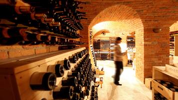 A wine cellar with rows of wine bottles on shelves and a brick archway.