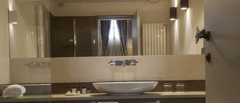 A modern bathroom with a large mirror, a bathtub, a sink, and a toilet.