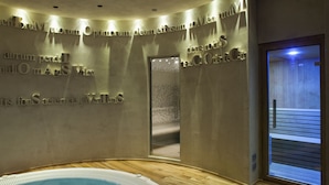 A spa area with a hot tub, wooden flooring, and a wall with engraved text. - Palazzo Righini (Fossano)