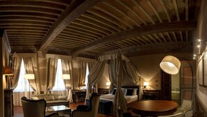 A spacious room with a large bed, a sitting area with a round table, and a separate desk. - Palazzo Righini (Fossano)