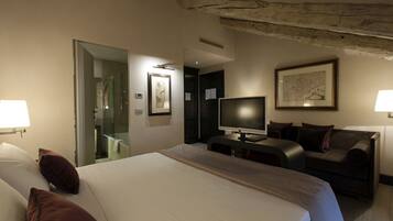 Een hotelkamer met een groot bed, een televisie, een bank en een bureau.