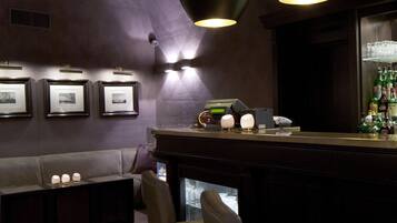 A bar area with a sofa, bar stools, and pendant lighting.