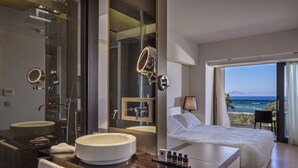 A modern hotel bathroom with a large mirror, a round sink, and a shower.