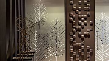 Un interior moderno con una pared decorativa que presenta motivos abstractos de hojas y formas geométricas.