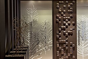 Un interior moderno con una pared decorativa que presenta motivos abstractos de hojas y formas geométricas.