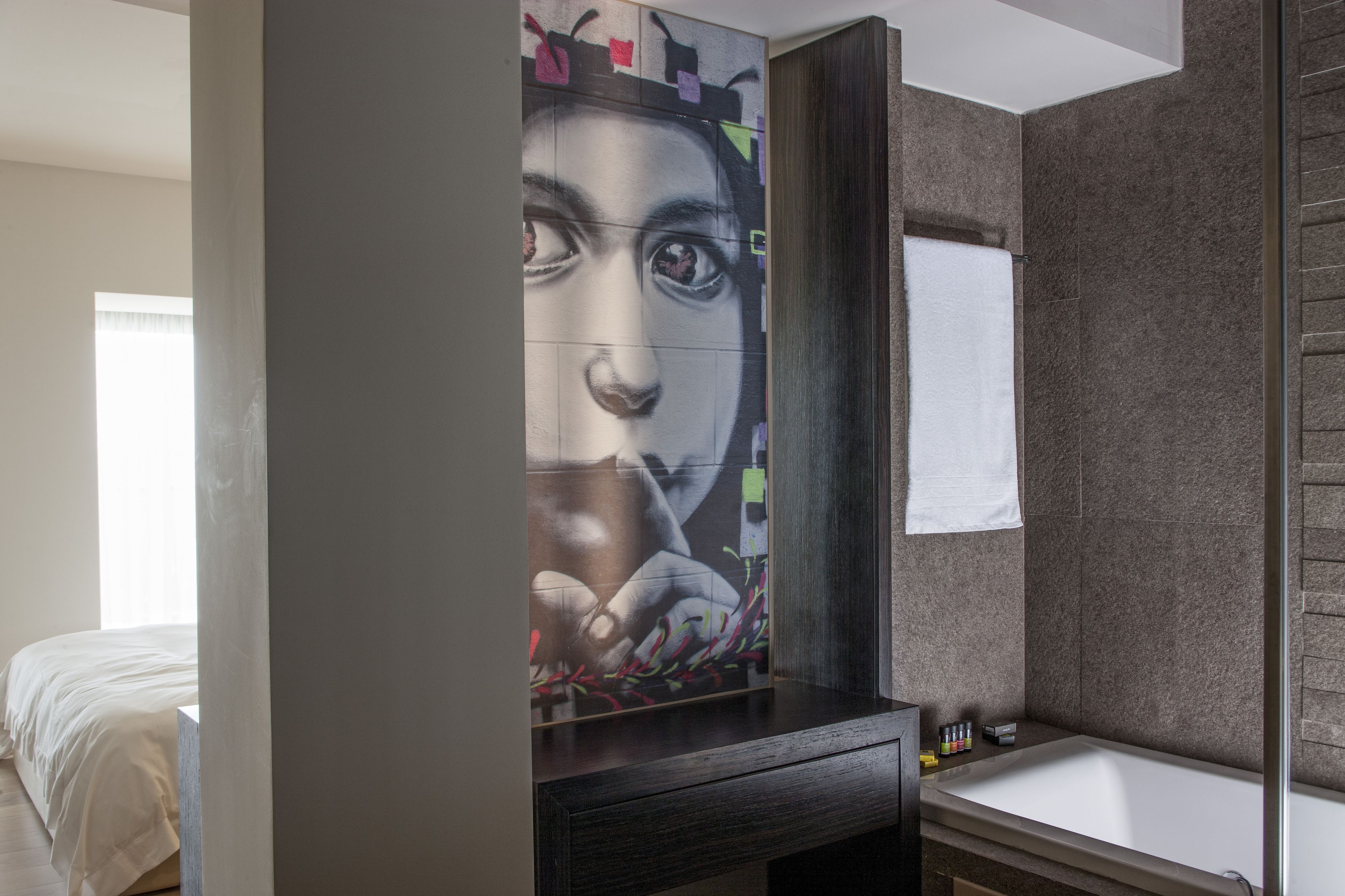 A modern bathroom with a large mirror, a bathtub, and a wall-mounted sink.