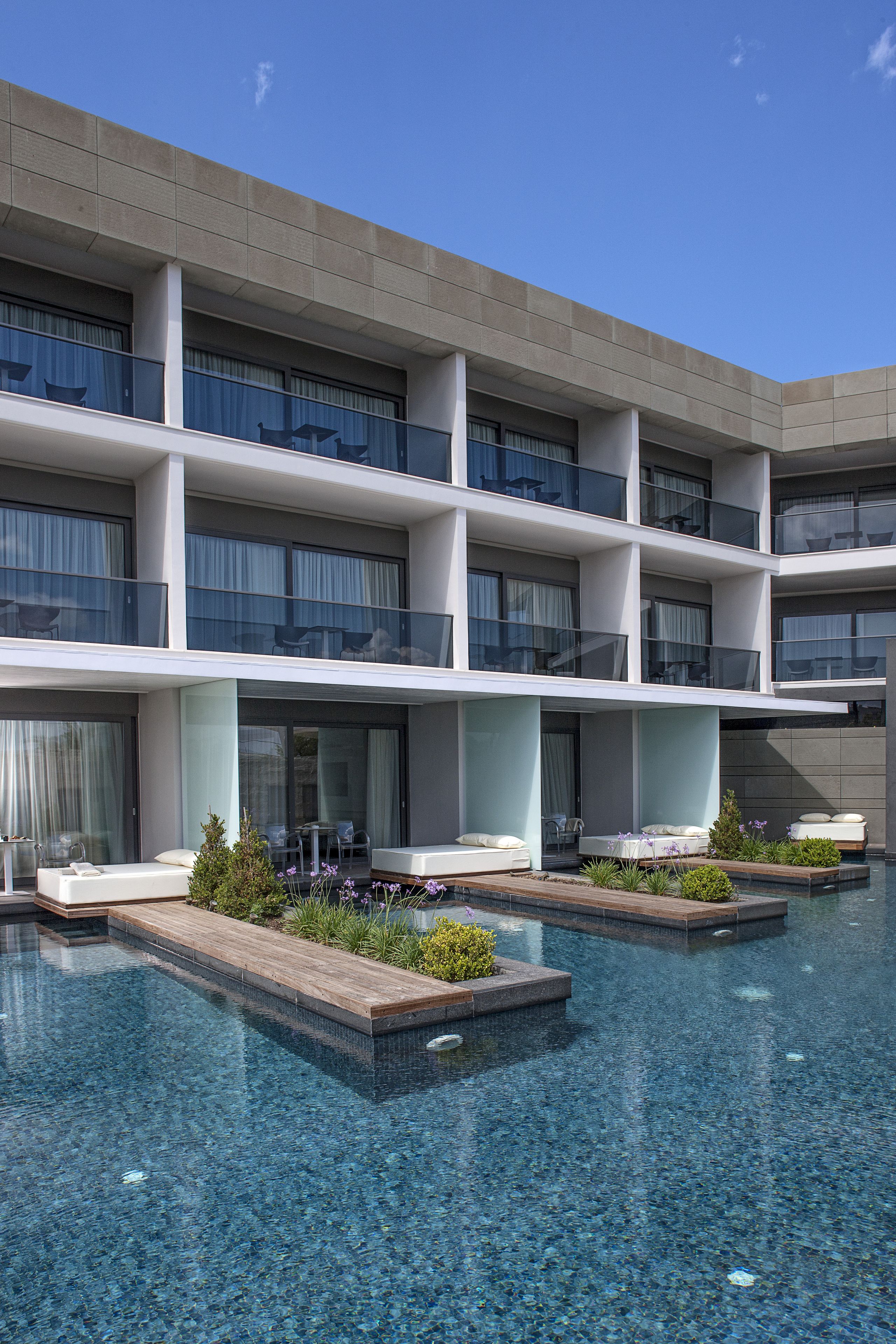 Un hôtel moderne doté d’une piscine, de nombreux balcons et d’un espace salon extérieur.