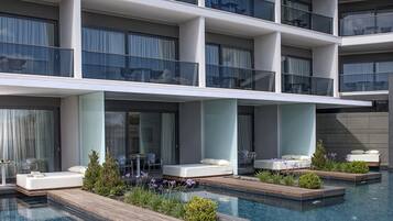 Un hotel moderno con zona de piscina, varios balcones y mobiliario exterior.