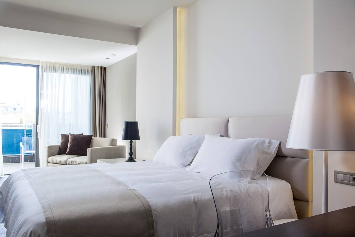 Een moderne hotelkamer met een groot bed, een bank, een bureau en een lamp.