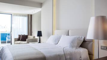 A modern hotel room with a large bed, a sofa, a desk, and a lamp.