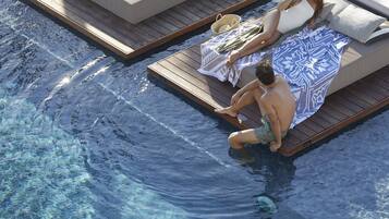 A poolside area with a wooden deck, lounge chairs, and a clear pool.