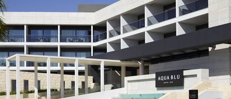 Un hôtel moderne doté d’une entrée imposante, de nombreux balcons et offrant une vue sur un ciel dégagé.