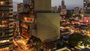 Un edificio alto y moderno con un logotipo destacado en la parte superior, rodeado de otros rascacielos en un paisaje urbano.