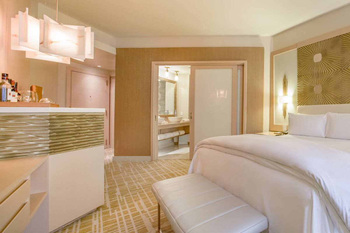 Una habitación de hotel con una cama grande, una mesita de noche, un armario y un espejo.