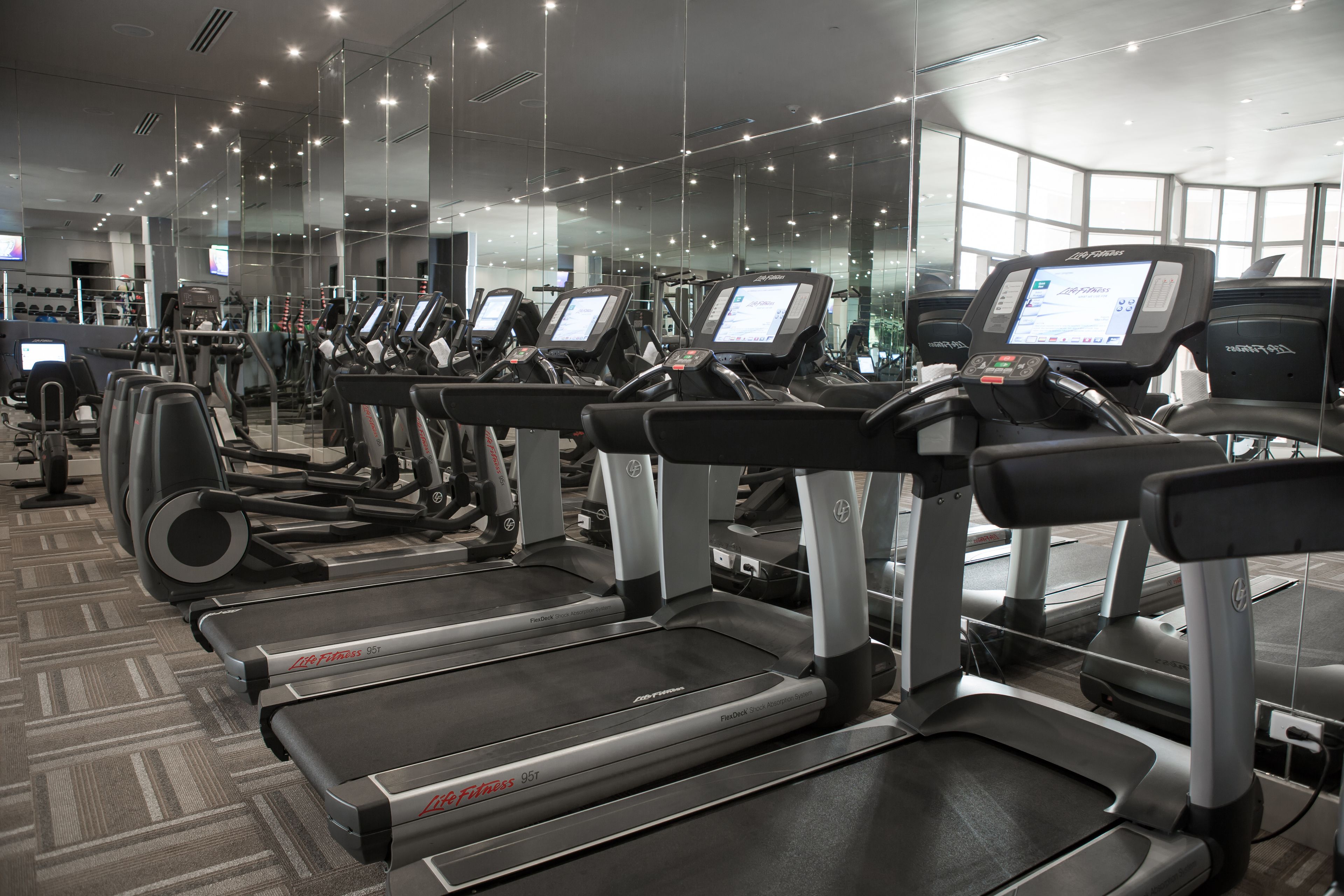 A gym with multiple treadmills, exercise bikes, and weight machines.