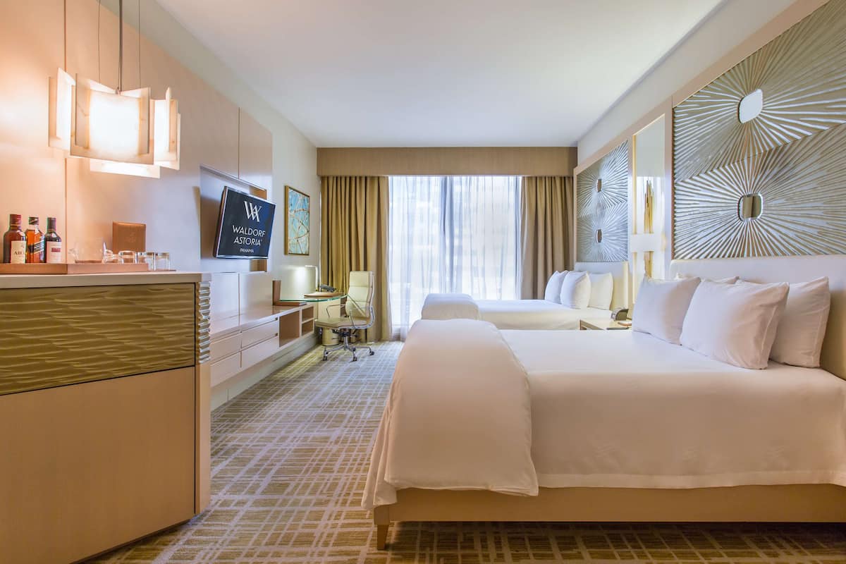 Habitación de hotel con una cama grande, un escritorio con computadora, un televisor y un mini bar.