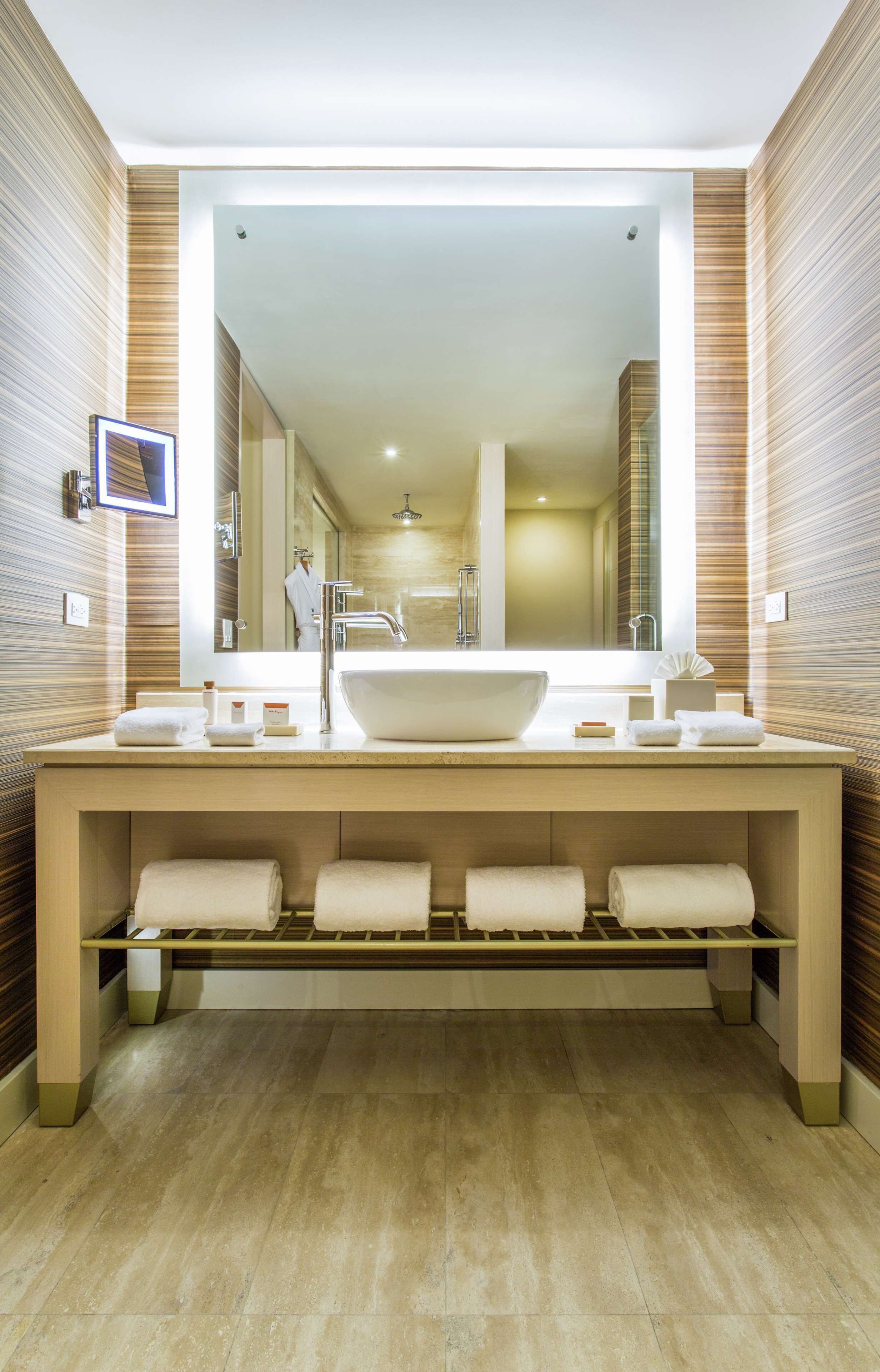 A modern bathroom with a large sink, multiple towel racks, and a large mirror.