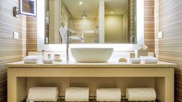 A modern bathroom with a large sink, multiple towel racks, and a large mirror.
