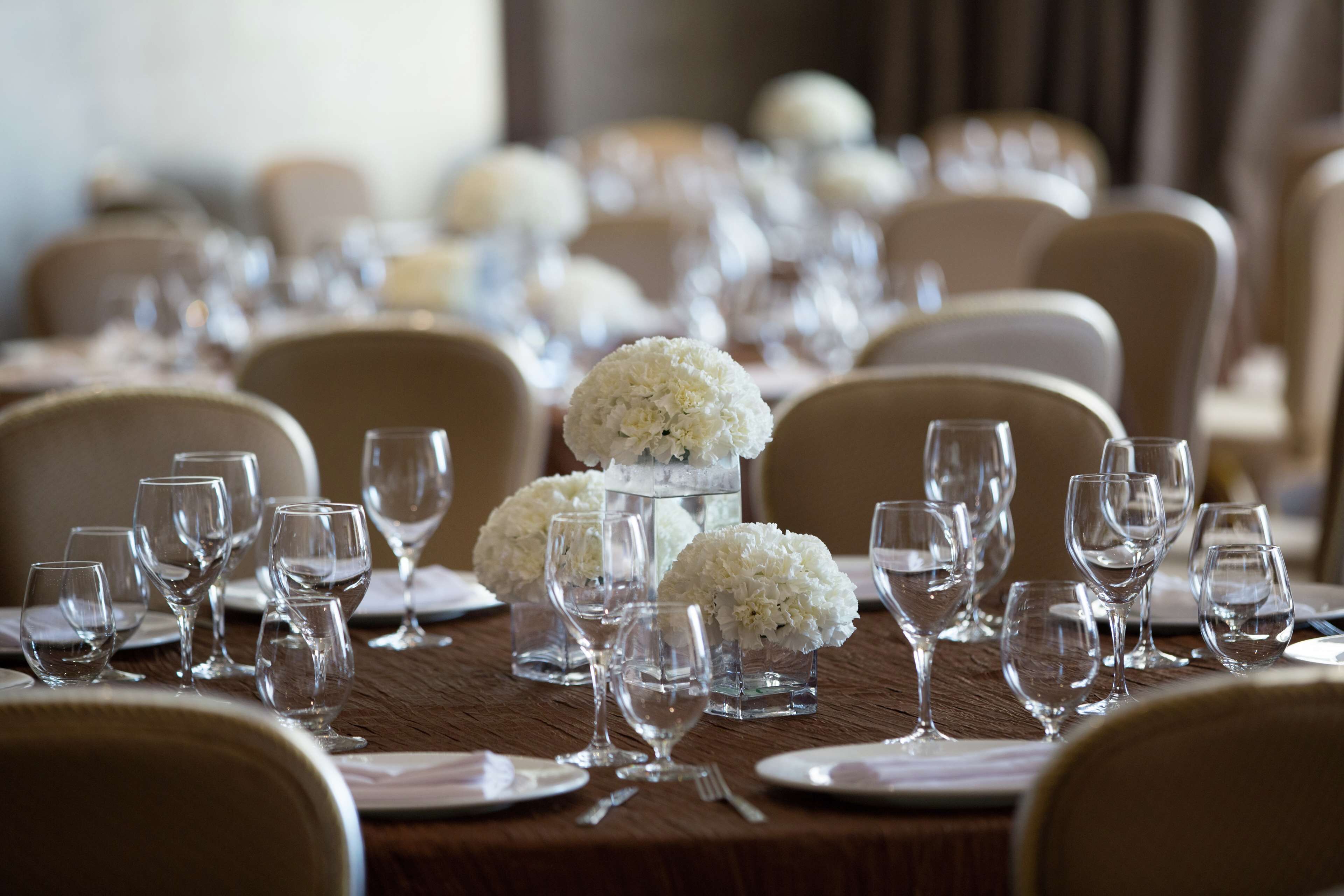 A formal dining table set with multiple wine glasses, water glasses, and white floral centerpieces.