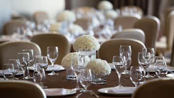 A formal dining table set with multiple wine glasses, water glasses, and white floral centerpieces.