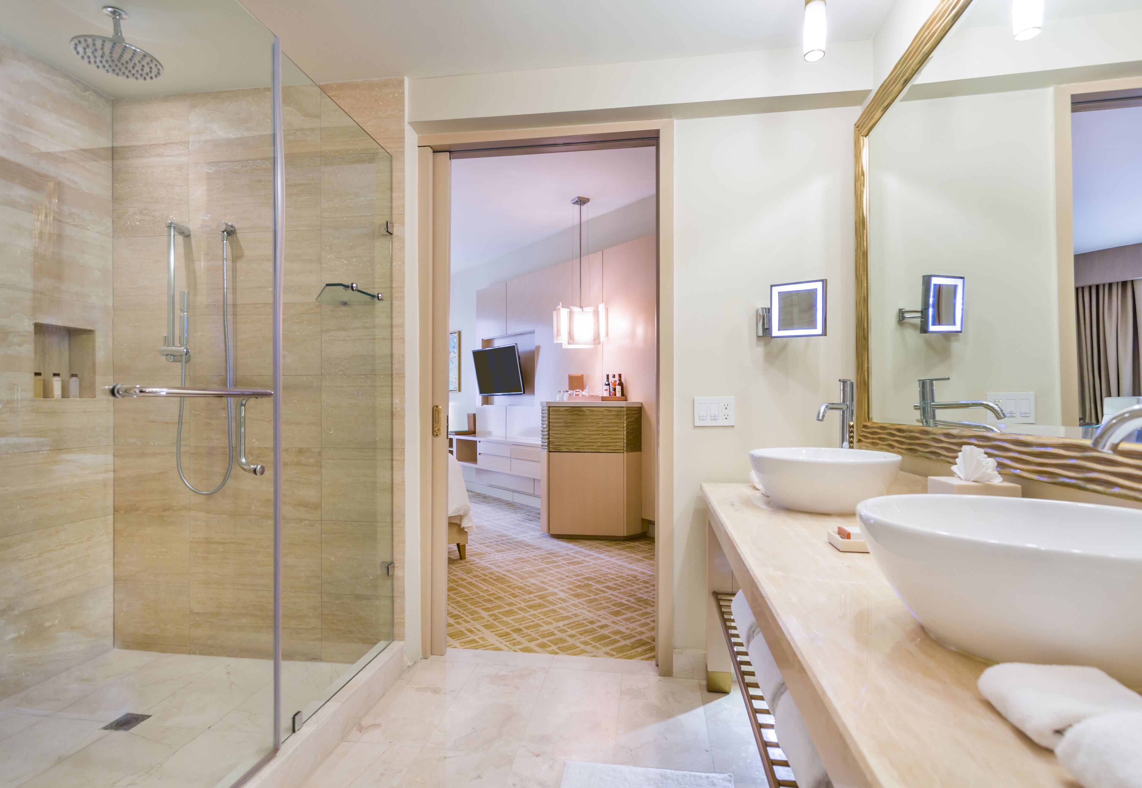 A modern bathroom with a glass-enclosed shower, two sinks, and a large mirror.