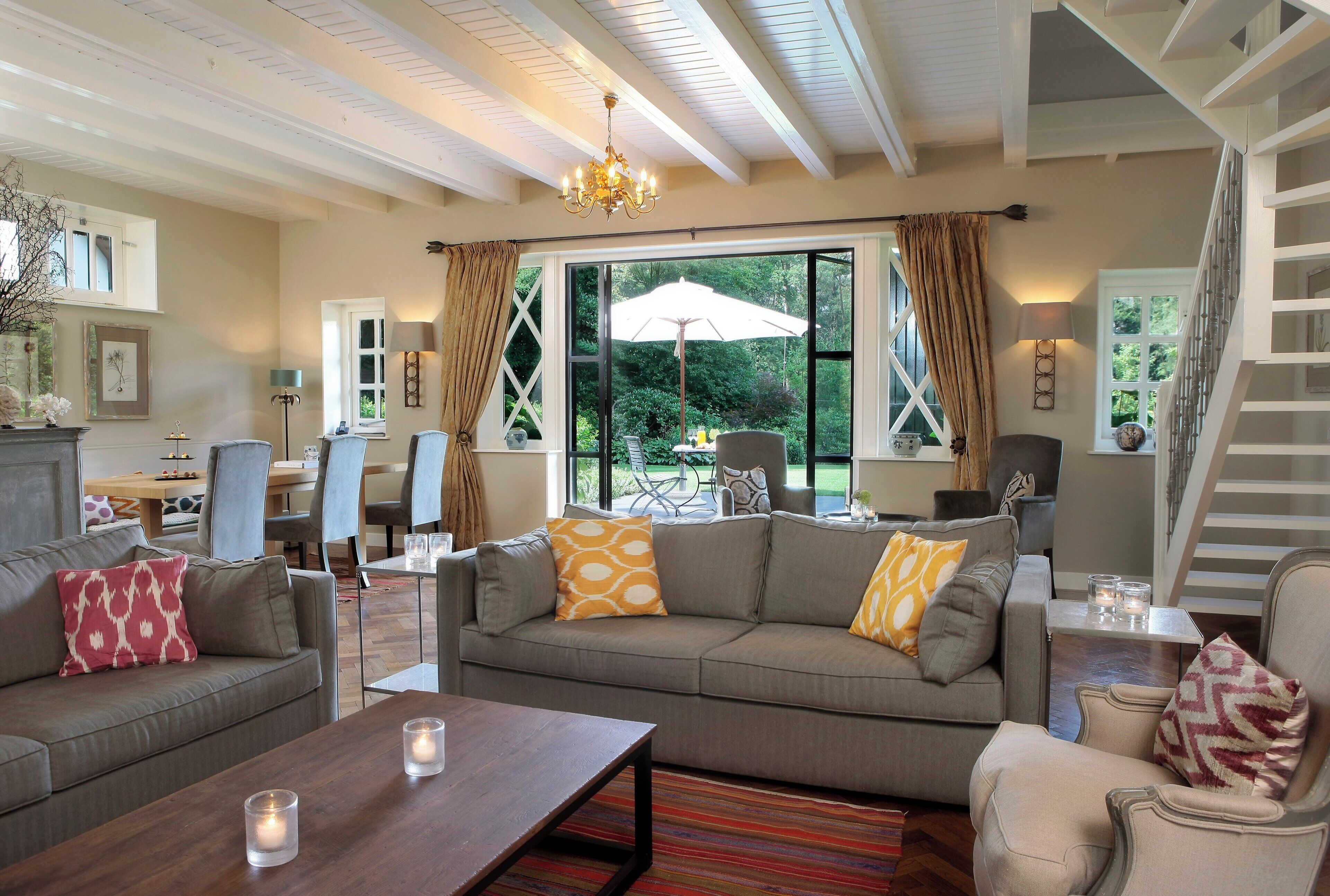 A spacious living room with a large grey sofa, a wooden coffee table, and a staircase leading to an upper level.