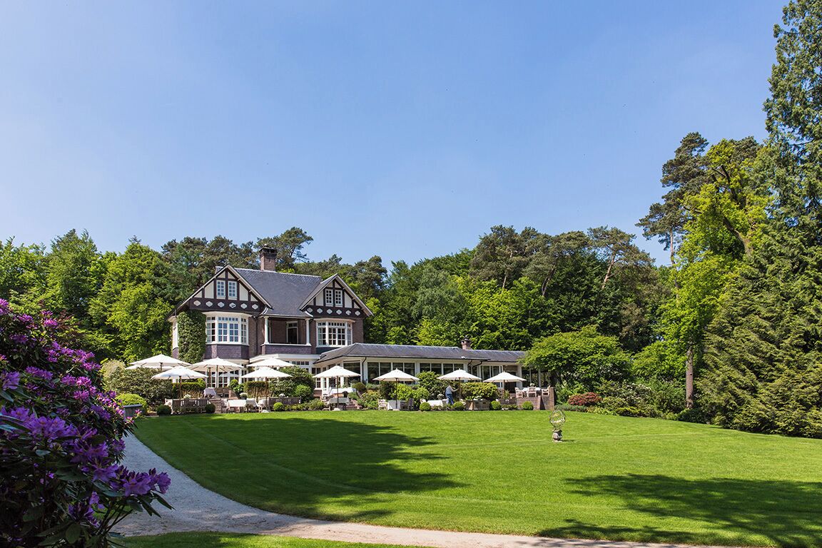 A large, traditional house with a well-maintained lawn and outdoor seating area.