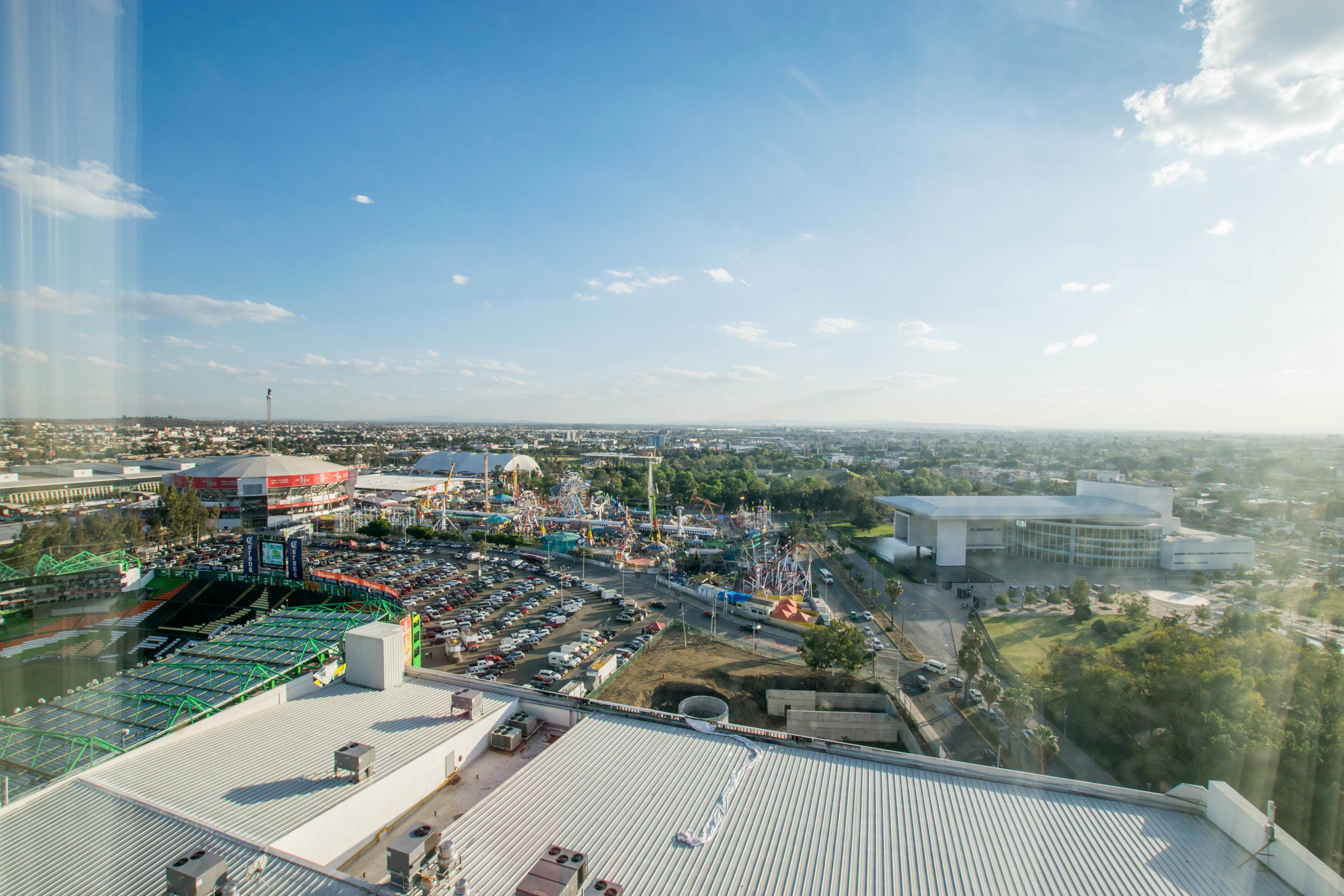 A high vantage point view of a cityscape with a large stadium, parking lots, and surrounding buildings.