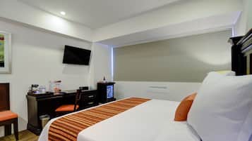 Una habitación de hotel con una cama, un escritorio con una silla, un televisor y una ventana con persianas.