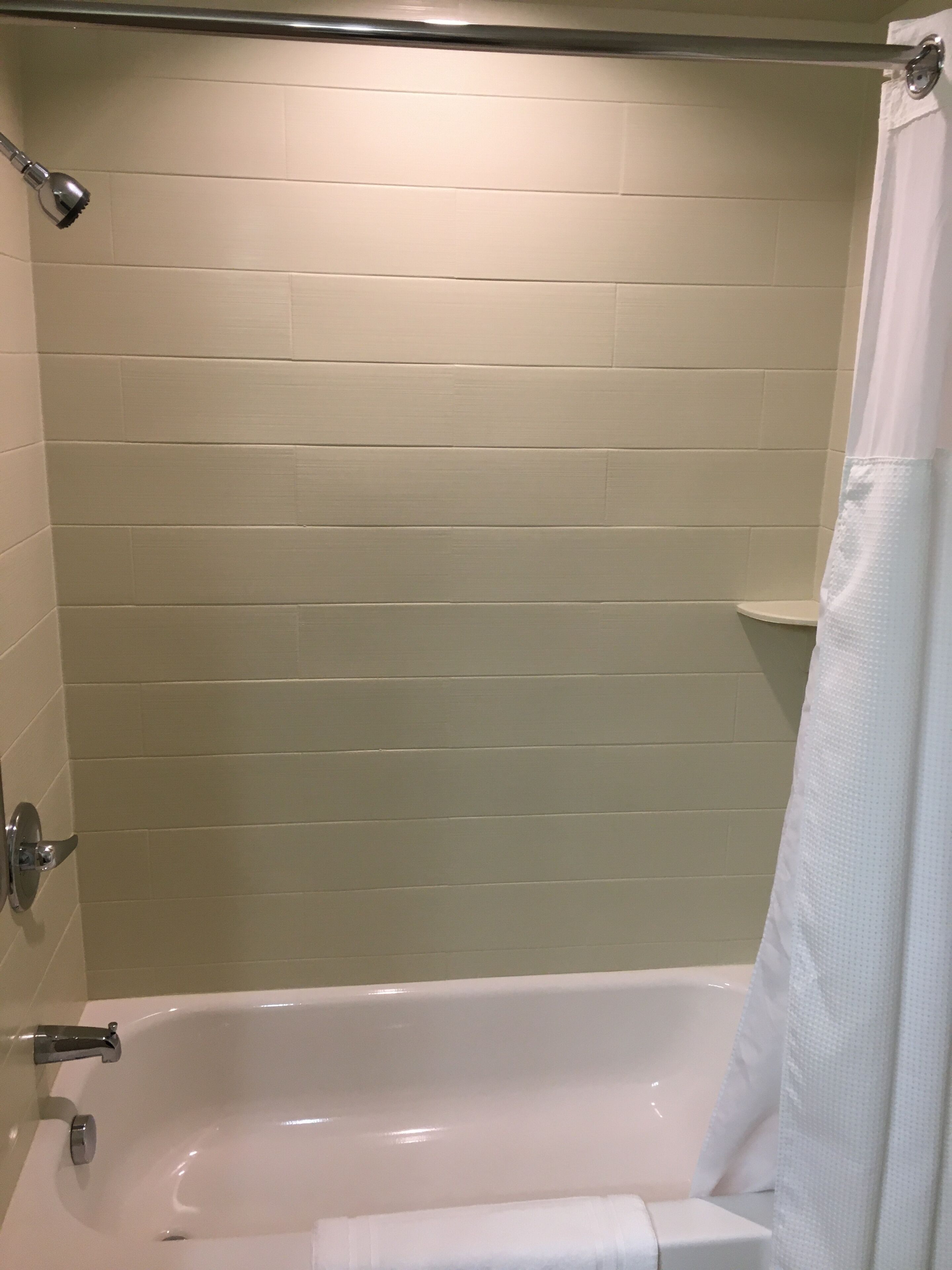 A bathroom with a bathtub, a showerhead, and a toilet.