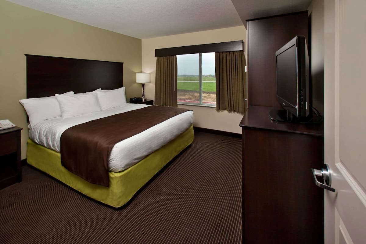 Ein Hotelzimmer mit einem großen Bett, einem Fernseher, einem Schreibtisch und einem Fenster mit Blick ins Freie.
