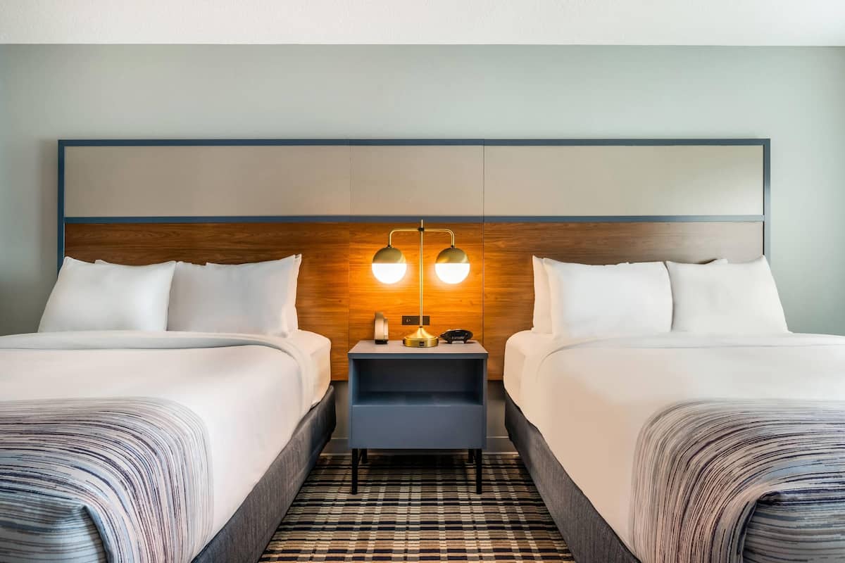 Ein Hotelzimmer mit zwei Betten, einem Nachttisch mit Lampe und einer Rezeption.