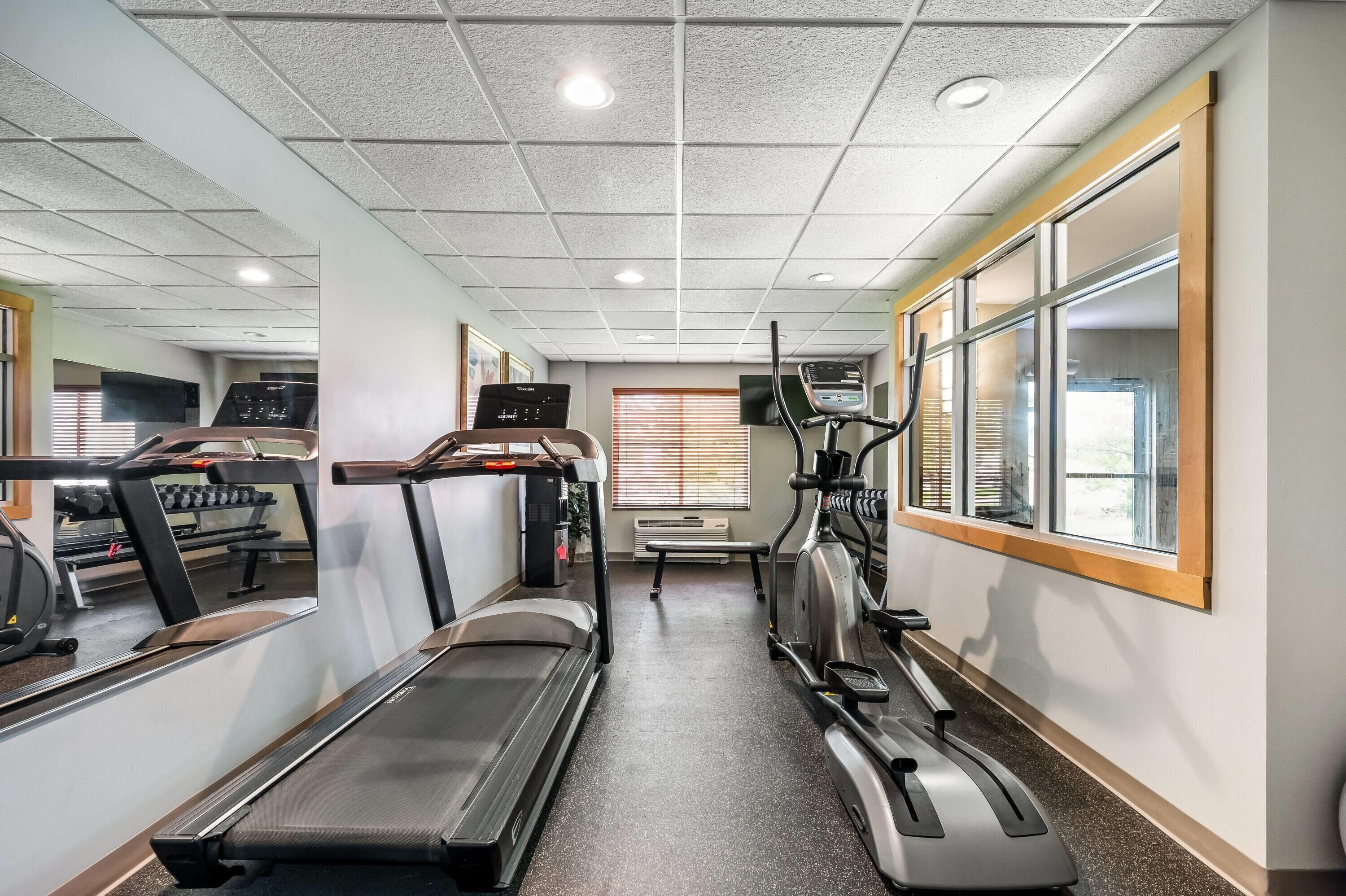 Une salle de sport équipée de tapis de course, d’un vélo d’appartement et d’un mur recouvert de miroirs.