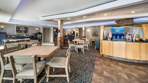 A spacious hotel lobby with multiple seating areas, a central bar, and a visible kitchen area. - AmericInn by Wyndham Fairfield (Fairfield)