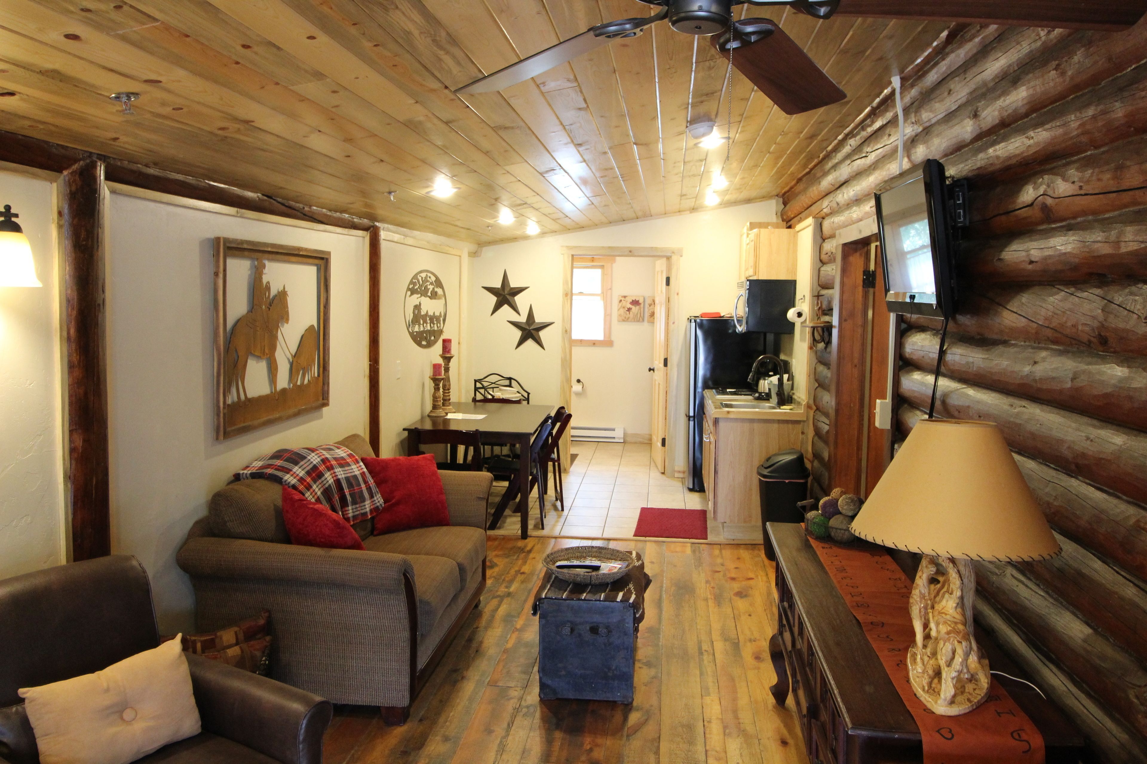 A cozy log cabin interior with a living room, dining area, and kitchen.