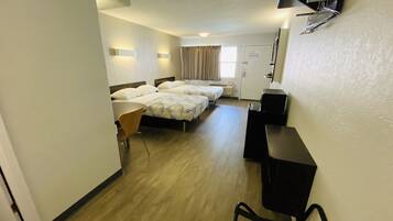 A hotel room with two single beds, a desk, a chair, a TV, and a door.