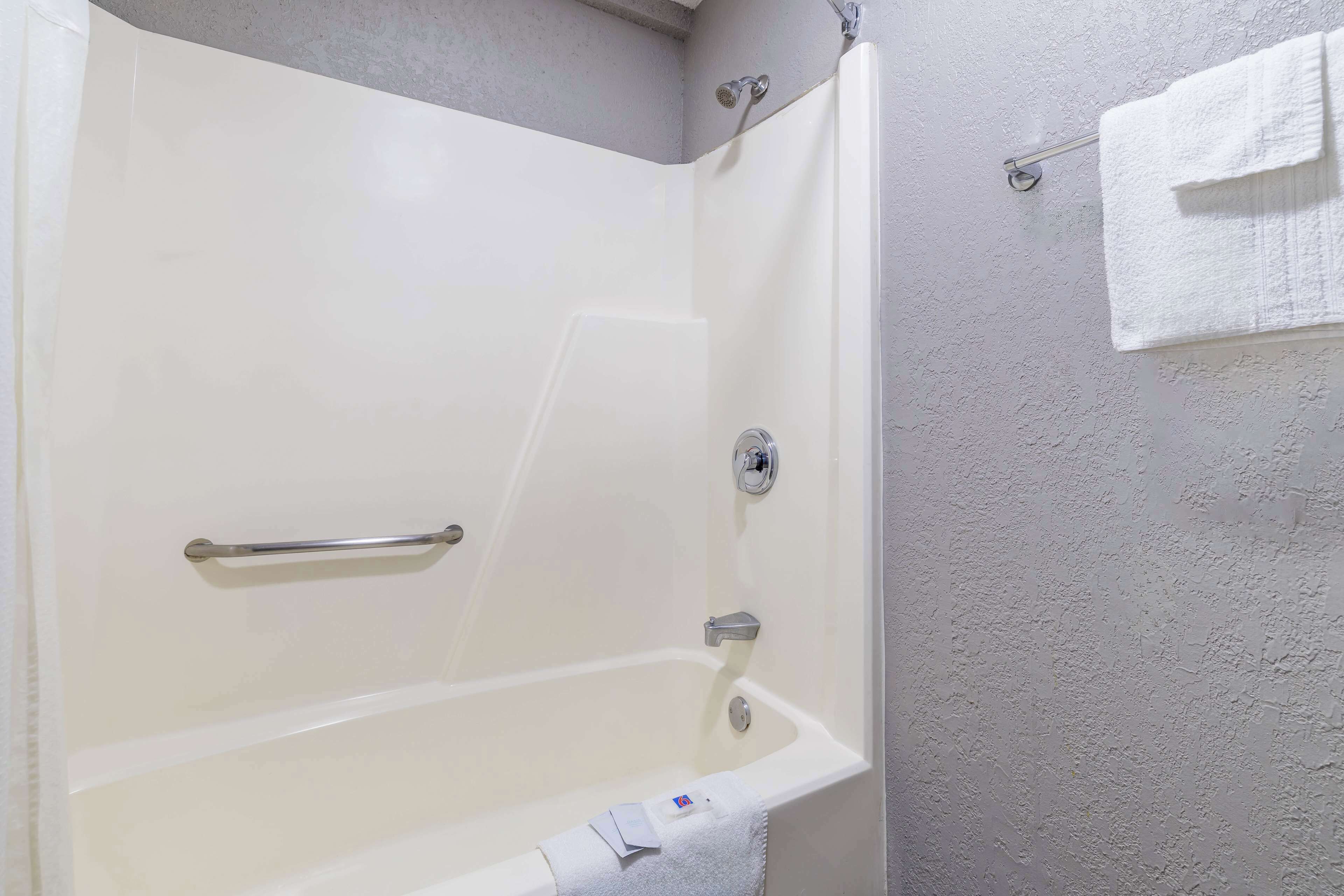 Une baignoire équipée d’une barre d’appui, d’un porte-serviettes et d’un pommeau de douche.
