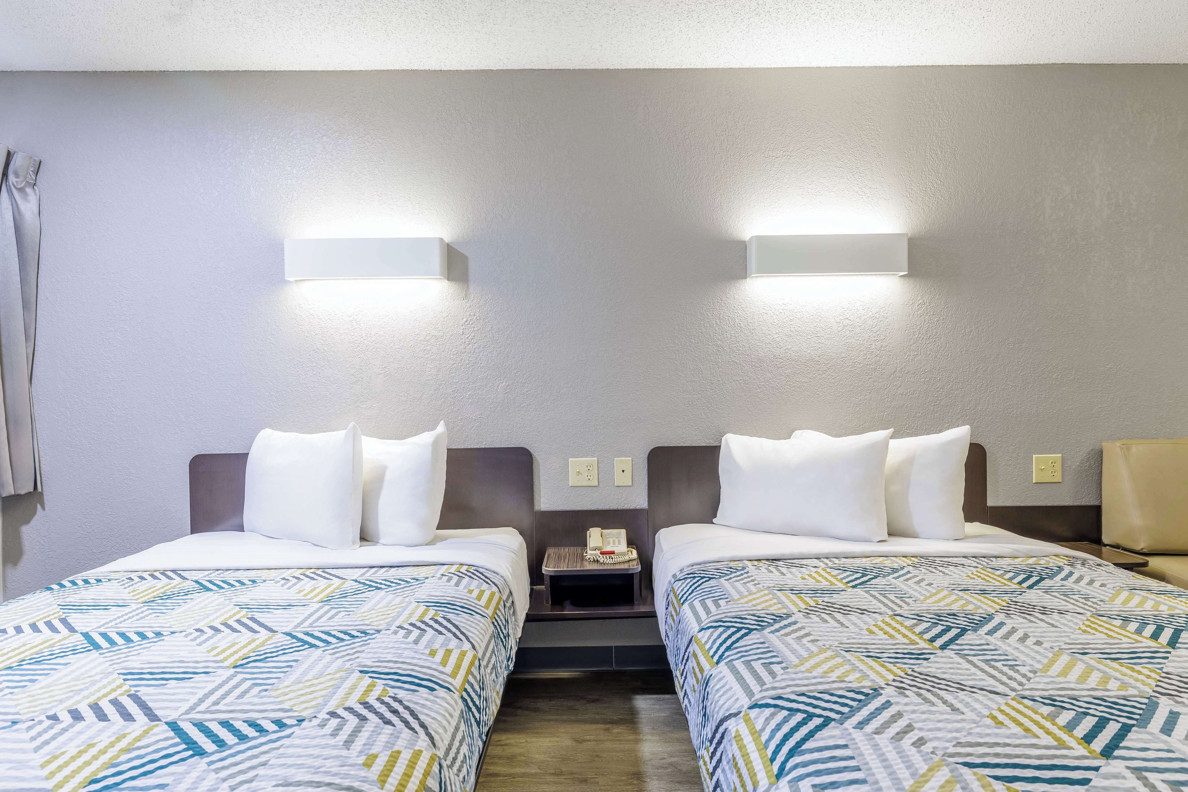 Une chambre d’hôtel avec deux lits, une table de chevet et un téléphone.
