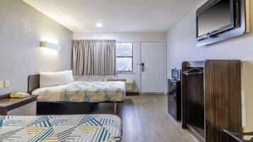 Quarto de hotel com duas camas, uma televisão presa à parede, uma mesa com telefone e um guarda-roupa.