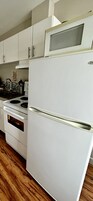 Una cocina con un refrigerador blanco, estufa y piso de madera.