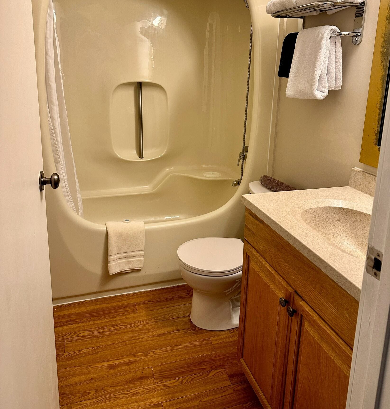 Un baño con bañera, inodoro y tocador de madera.