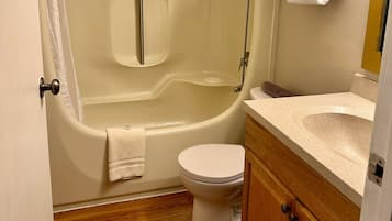 Un baño con bañera, inodoro y tocador de madera.