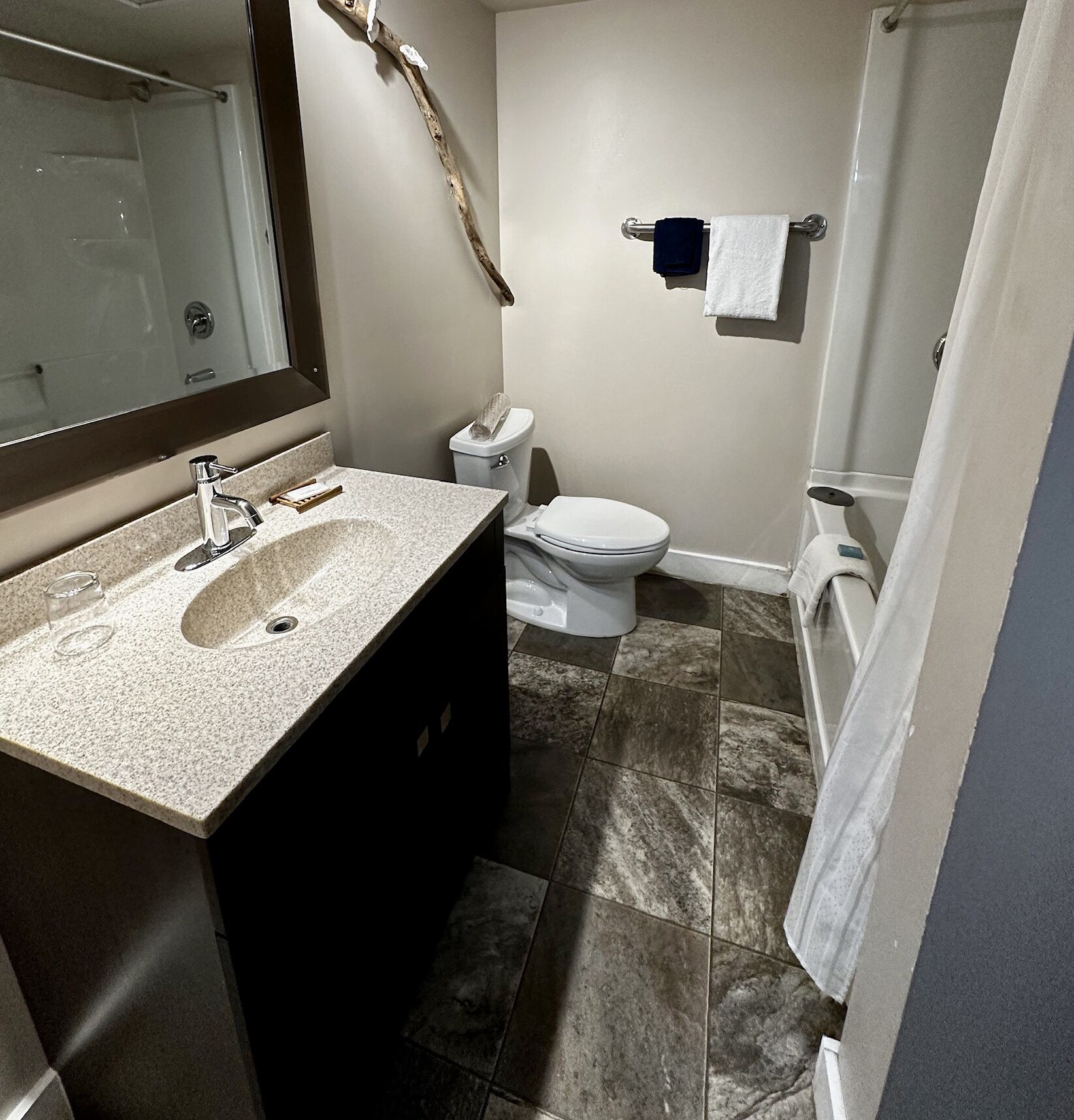 Une salle de bain avec un lavabo en granit, des toilettes et une douche.