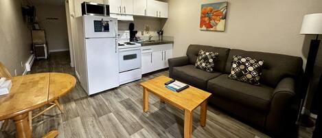 A compact living space with a kitchenette, a sofa, a coffee table, and a dining area.