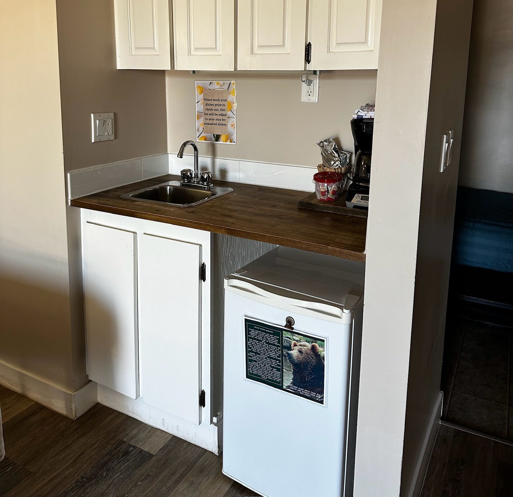 A compact kitchen with a sink, a small refrigerator, and a coffee maker.