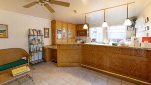 A kitchen with wooden cabinets, a ceiling fan, pendant lights, and a counter with various items. - Murphys Inn Motel (Murphys)